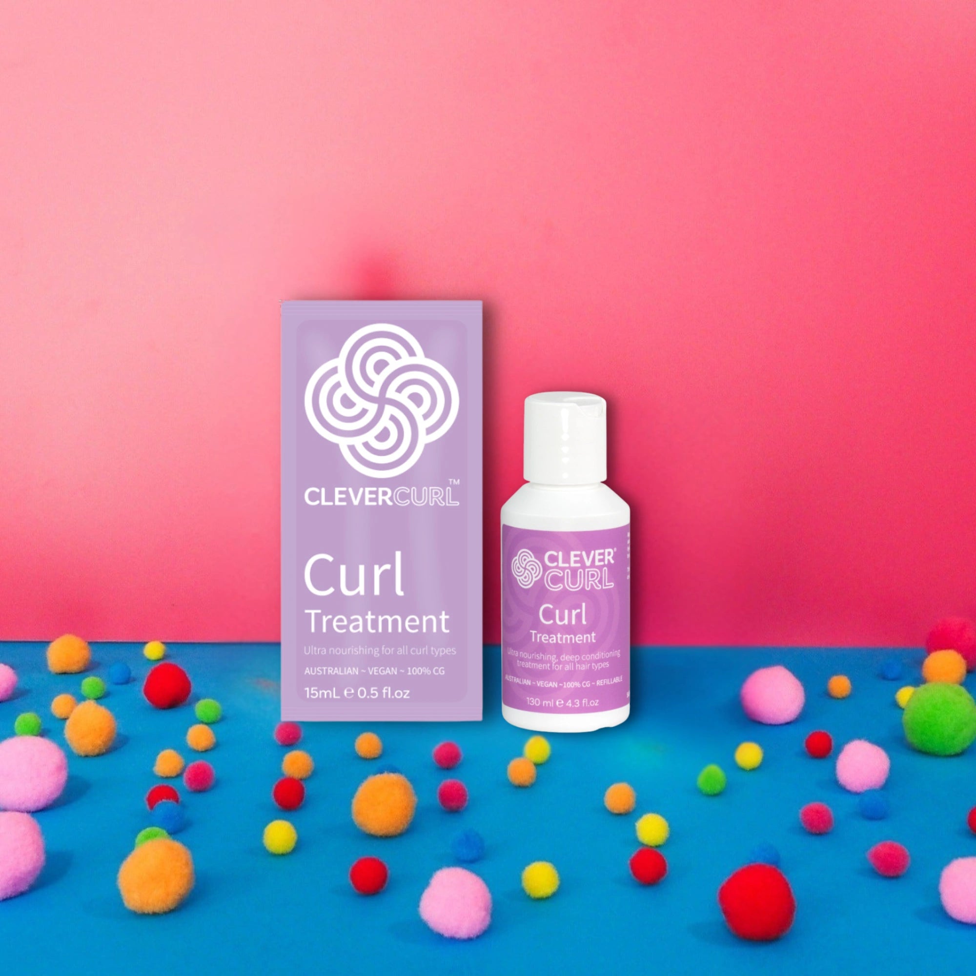 Clever Curl treatment packaging and bottle on a pink and blue background with colorful pom-poms at Curly Tops